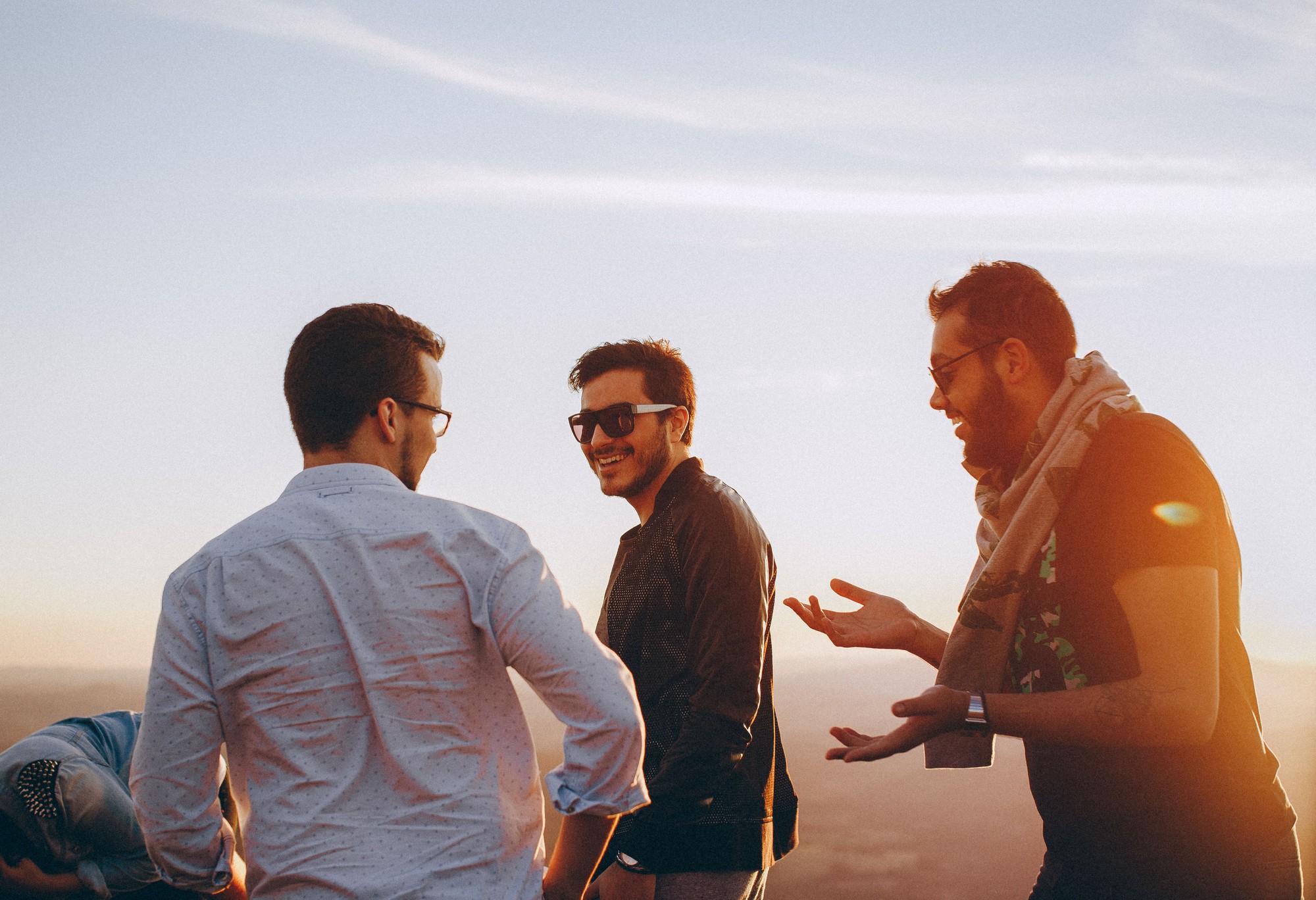 Three friends talking and laughing together at sunset