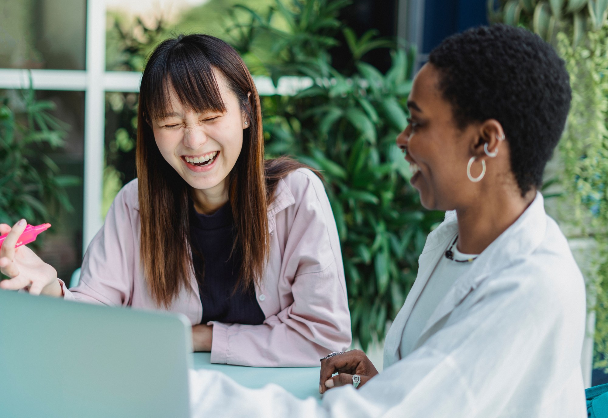 Two friends sharing a laugh over a laptop